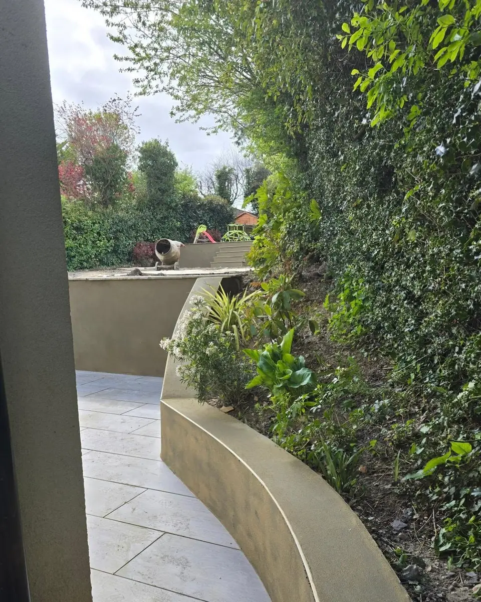 Curved rendered garden wall beside planting and paving, by ST Plastering & Rendering